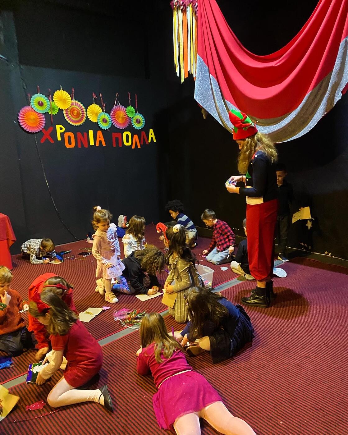 Children sitting on the floor with an entertainer, under a ‘HAPPY BIRTHDAY’ banner